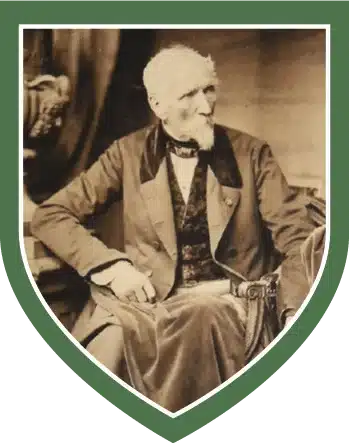 Old photograph of an elderly Myles Byrne, with white hair and a beard, seated and wearing a formal suit, framed within a green shield border, featured at the National 1798 Rebellion Centre, Enniscorthy.