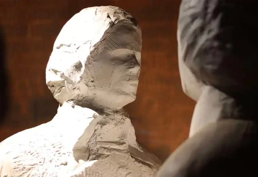 Close-up of rough-textured sculpted figures facing each other in a dimly lit exhibition display, featured in the National 1798 Rebellion Centre, Enniscorthy.