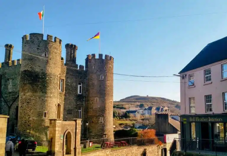 Enniscorthy Castle with Irish and county flags flying, overlooking the town and Vinegar Hill in the background, on a clear day.