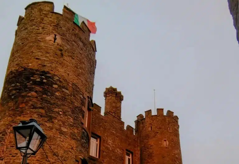 Close-up view of the stone towers of Enniscorthy Castle with the Irish flag flying above.