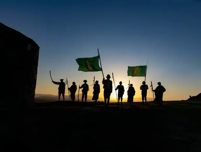 Silhouetted 1798 Rebellion reenactors holding pikes and green flags at sunset, standing on a hilltop, featured at the National 1798 Rebellion Centre, Enniscorthy.