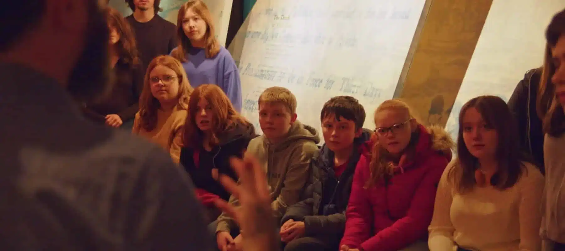 Young visitors seated in a group listening to a guide during an educational talk inside the National 1798 Rebellion Centre, Enniscorthy.